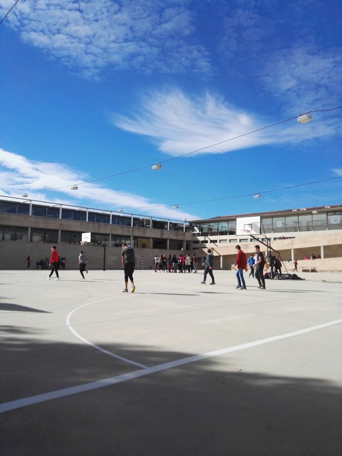 Accueil People playing basketball on an outdoor court under a blue sky.